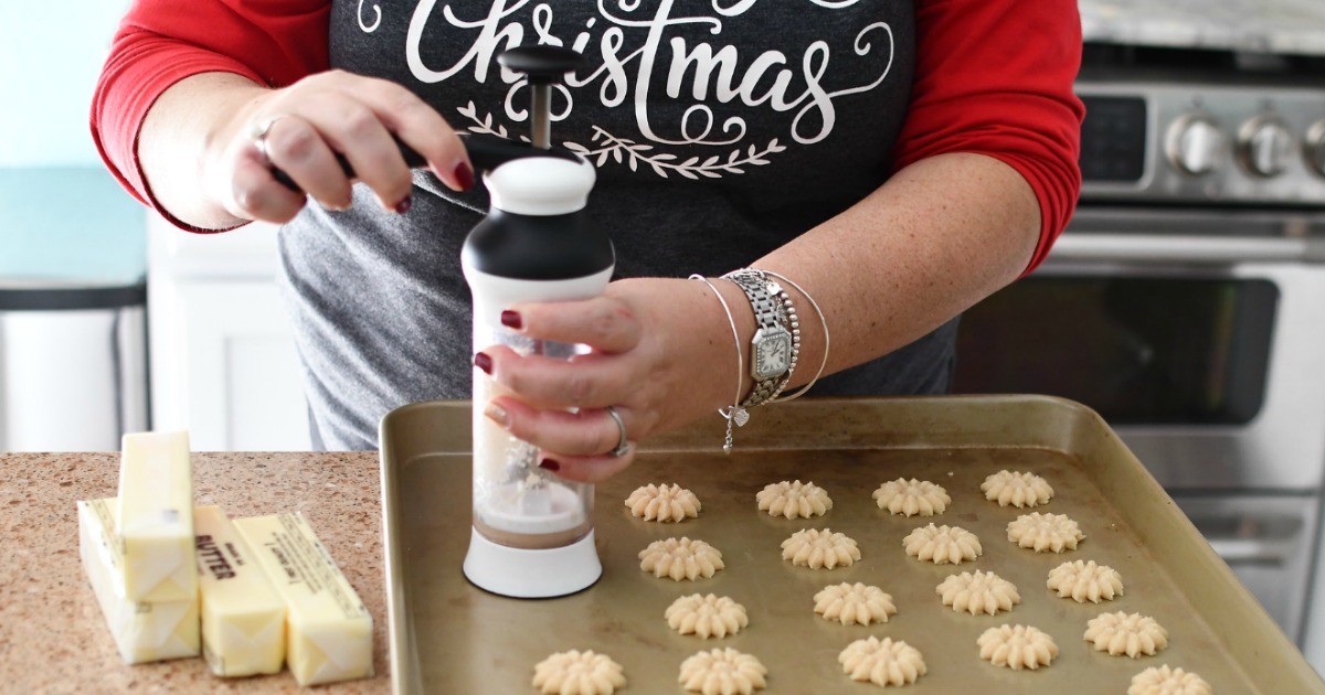 woman using cookie press to make Christmas cookies 
