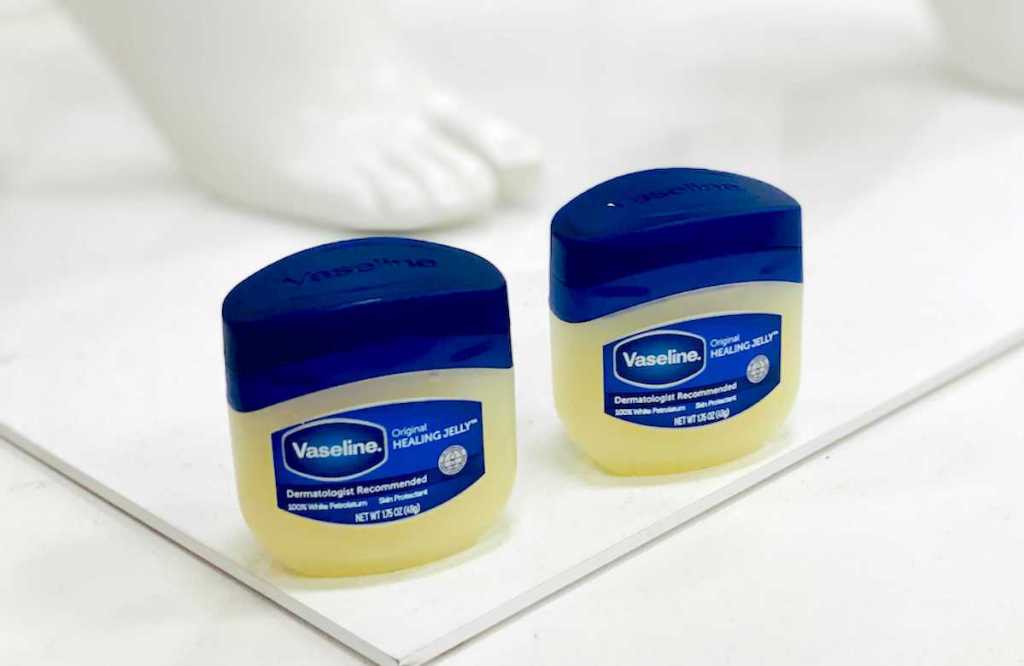 two bottles of vaseline in front of white plastic foot
