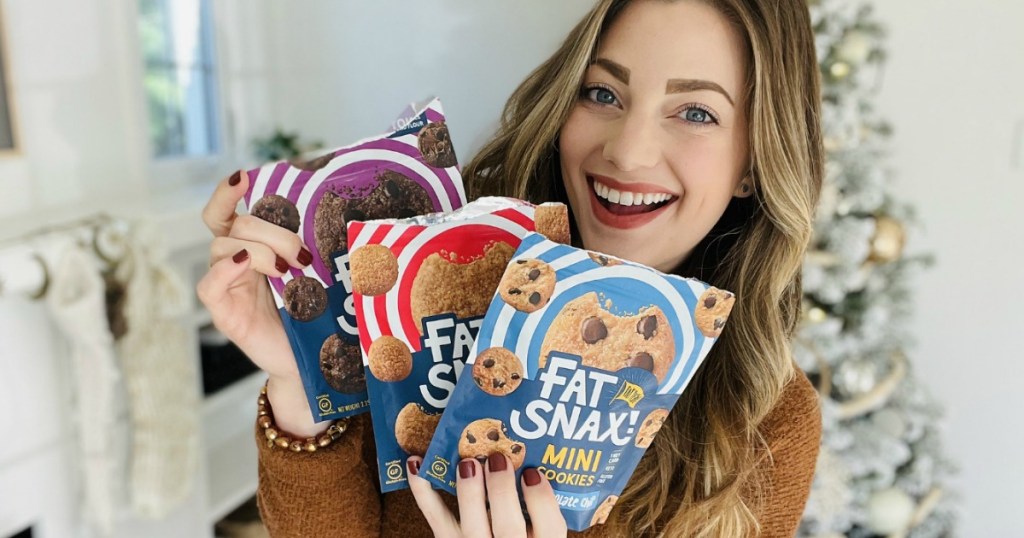 woman holding Fat Snax in front of Christmas tree 