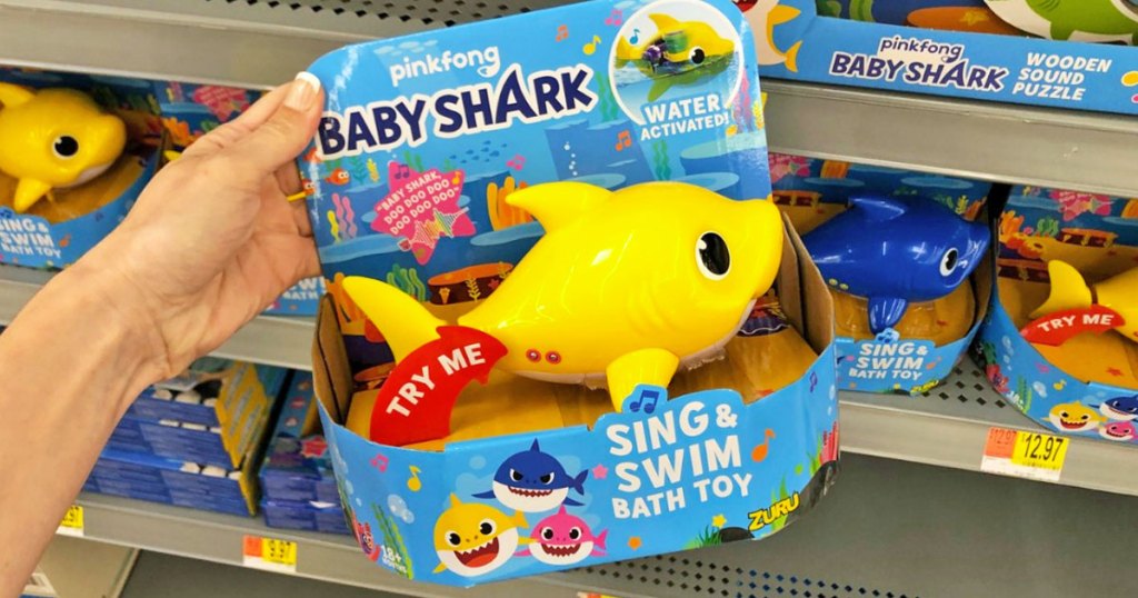 woman holding up a yellow baby shark bath toy at walmart