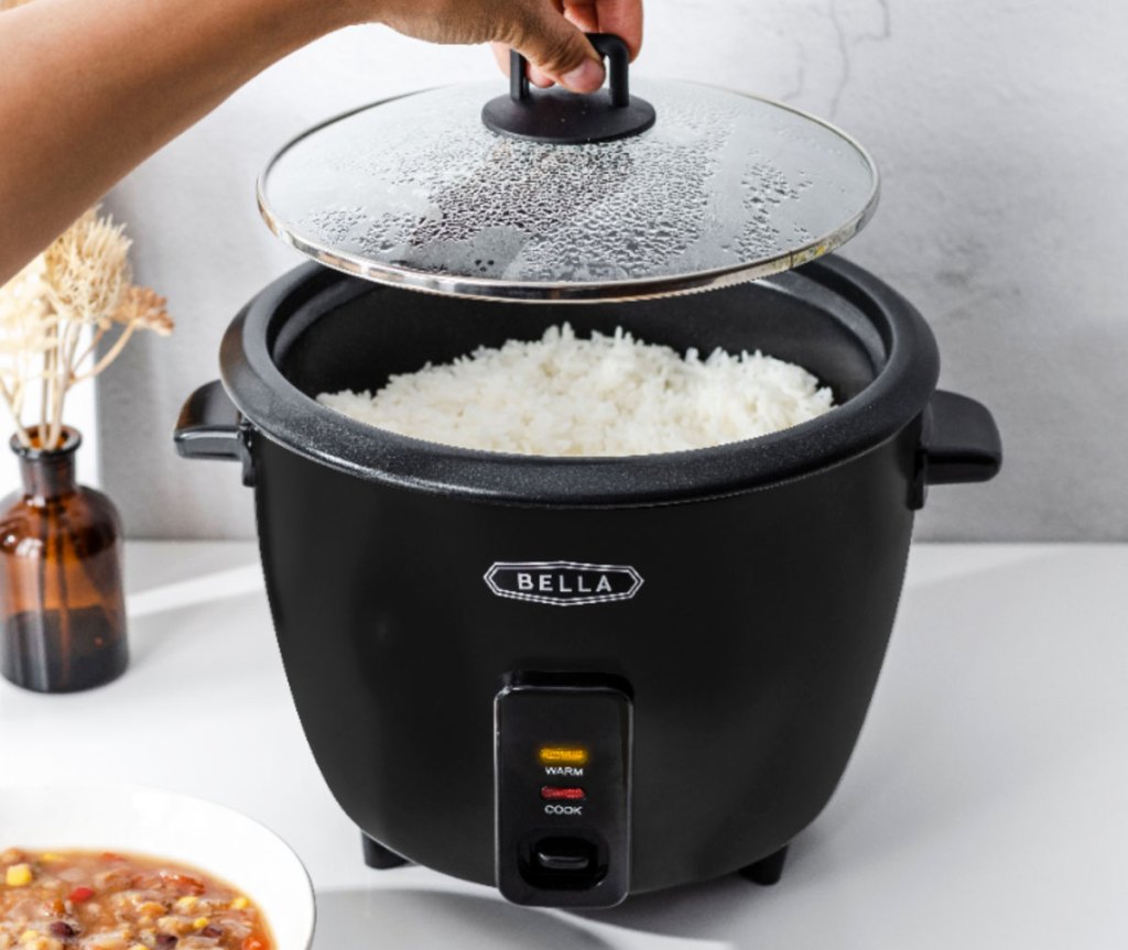 person lifting glass lid off the top of a black rice cooker