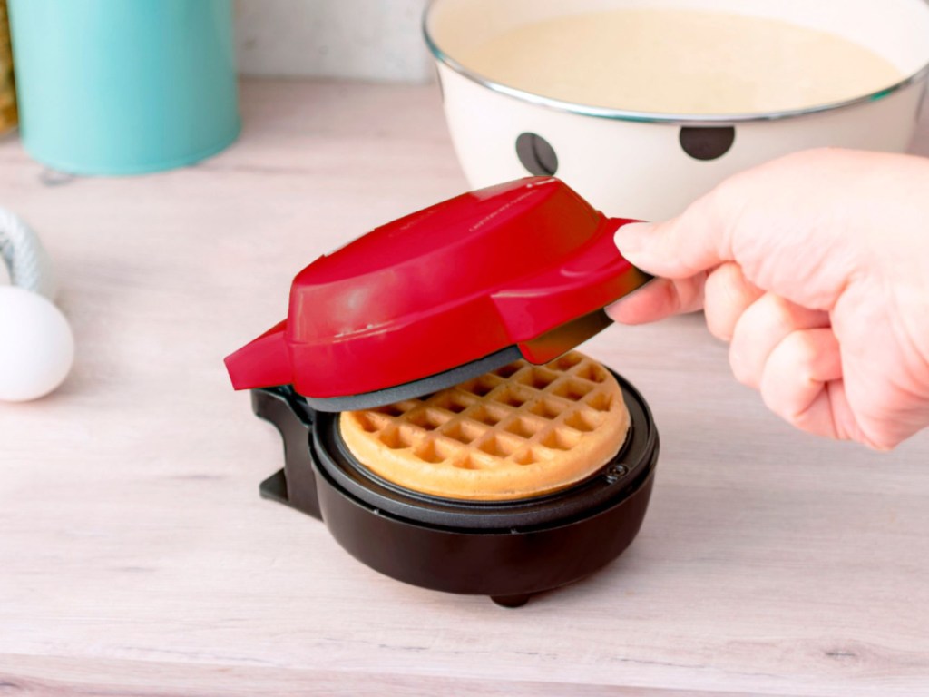 hand holding the lid of a small bella waffle maker
