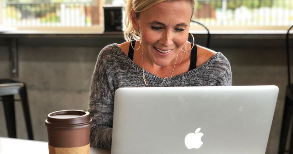 woman with blonde hair working on a macbook with cup of coffee