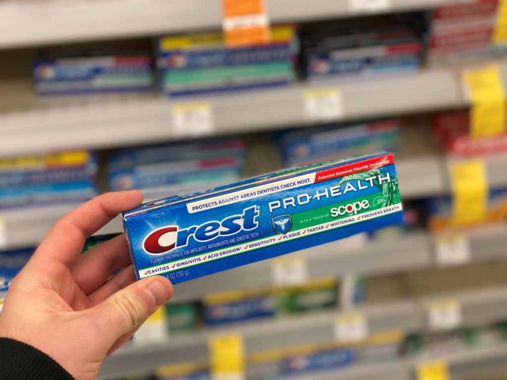 hand holding a box of Crest toothpaste