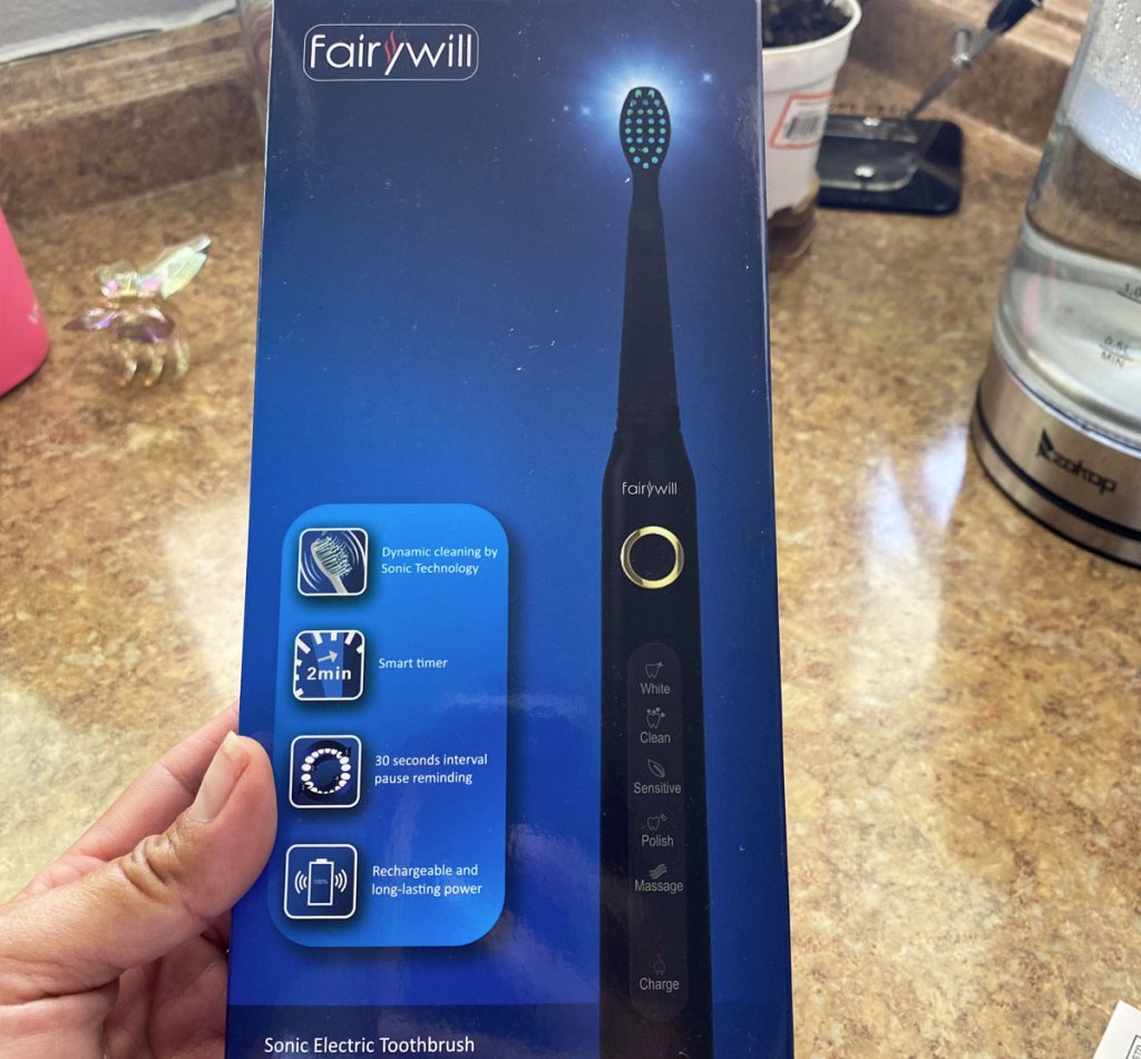 person holding box for a black electric toothbrush