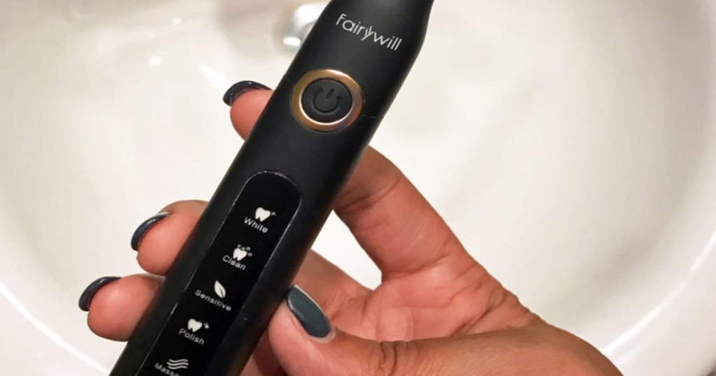 woman with grey nails holding a black electric toothbrush