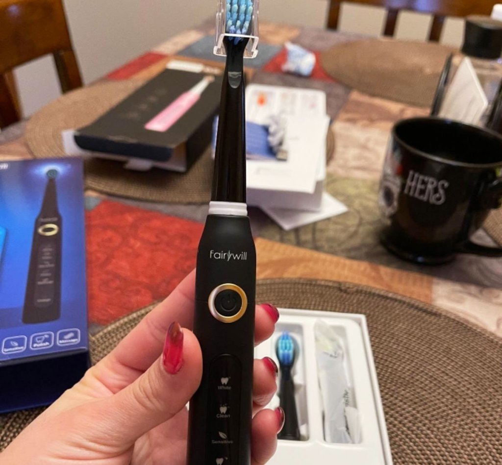 person holding up a black electric toothbrush