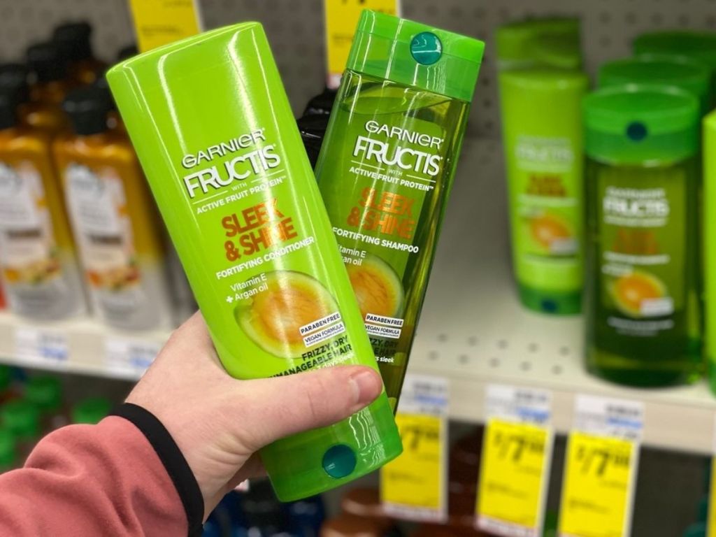 woman holding two bottles Garnier Fructis shampoo and conditioner