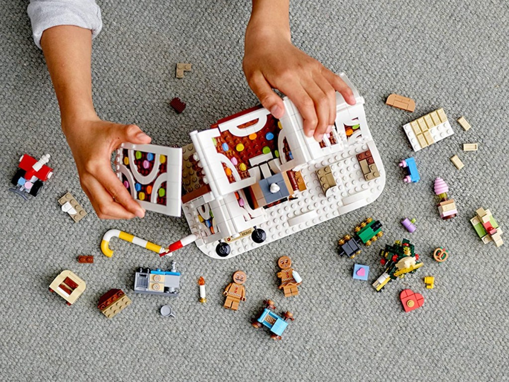 child's hands playing with LEGO Gingberbread set on floor