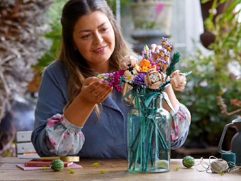 woman sitting down putting together a lego bouquet set