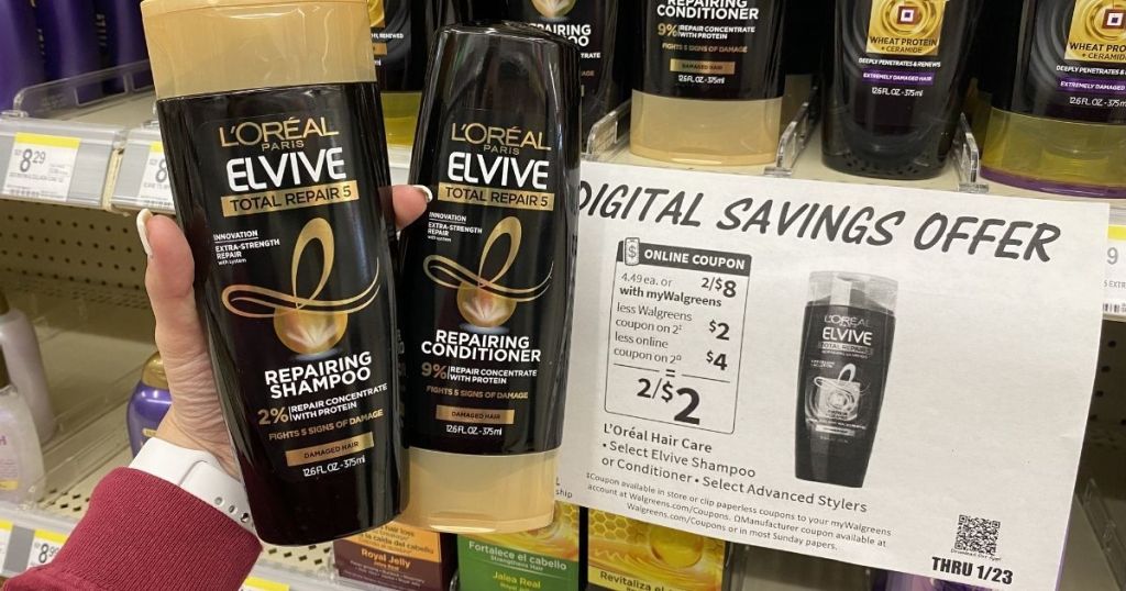 hand holding both L'Oreal Elvive Shampoo and Conditioner in front of sign in-store