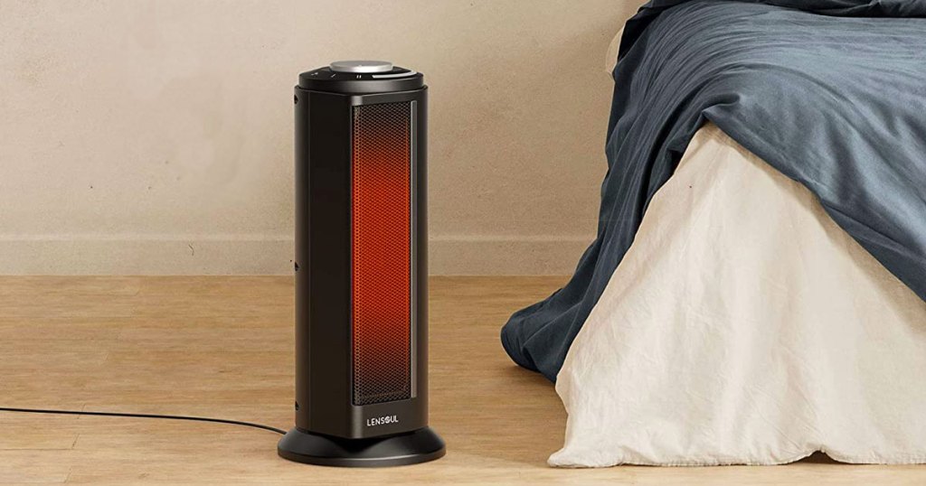 black tower space heater on floor next to a bed