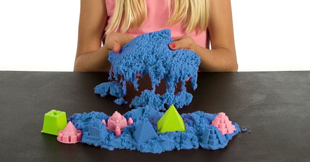 girl playing with blue Kinetic sand with castle molds