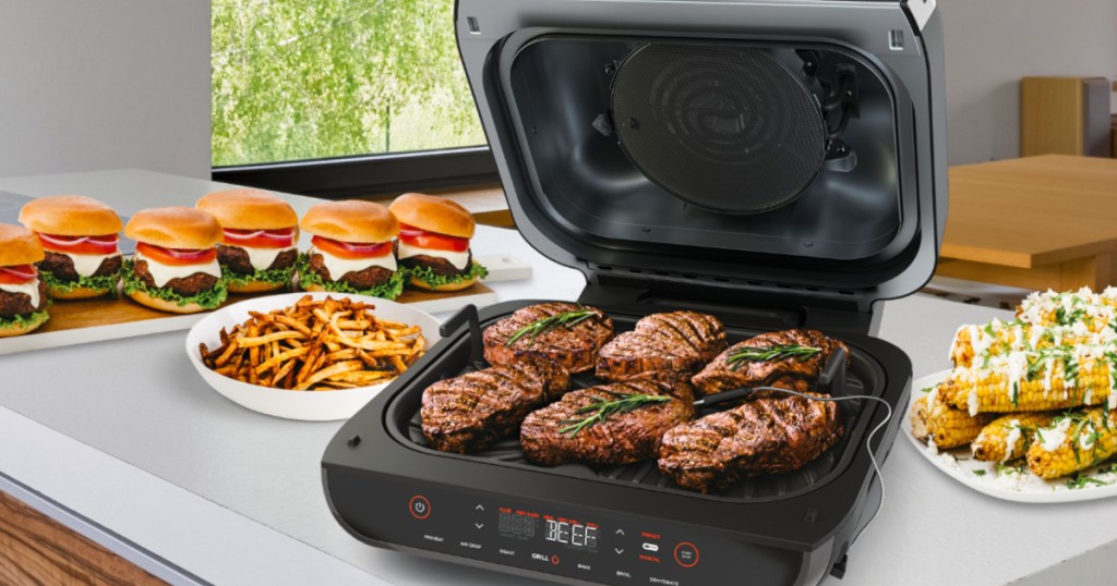 Ninja Foodi 6-in-1 Smart XL Indoor Grill with Air Fryer with steaks on the grill, hamburgers behind it