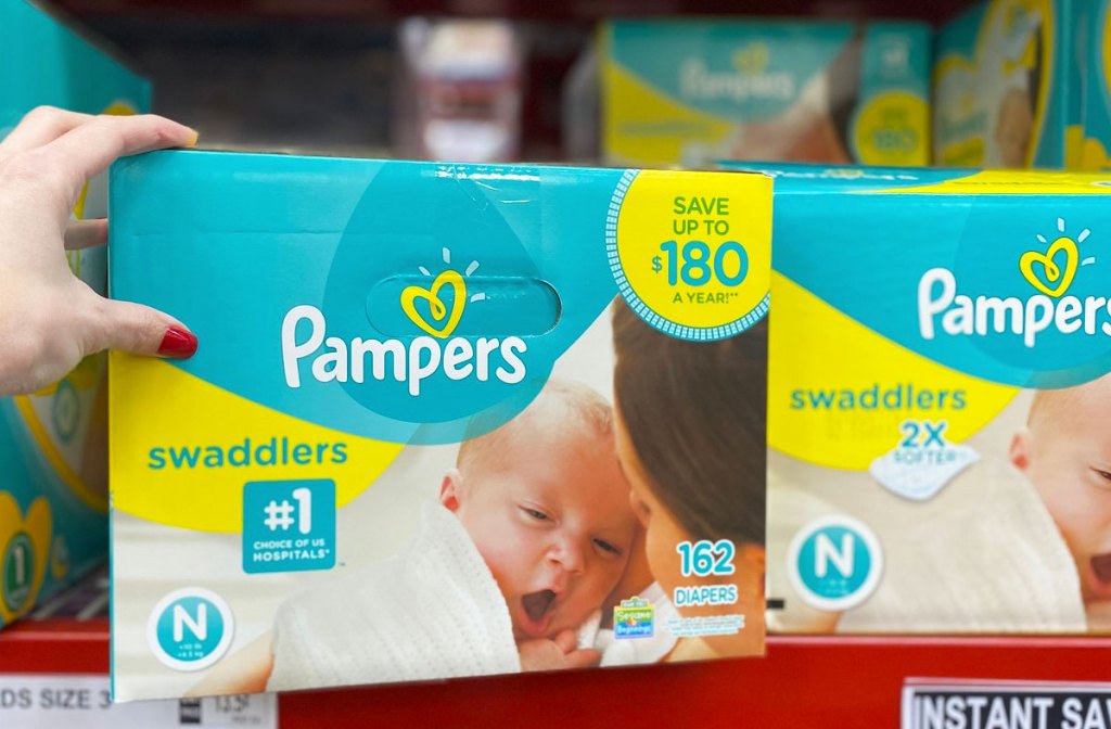 woman holding box of pampers diapers on shelf at sams club