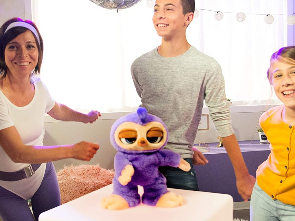 family dancing with purple sloth dancing toy in living room