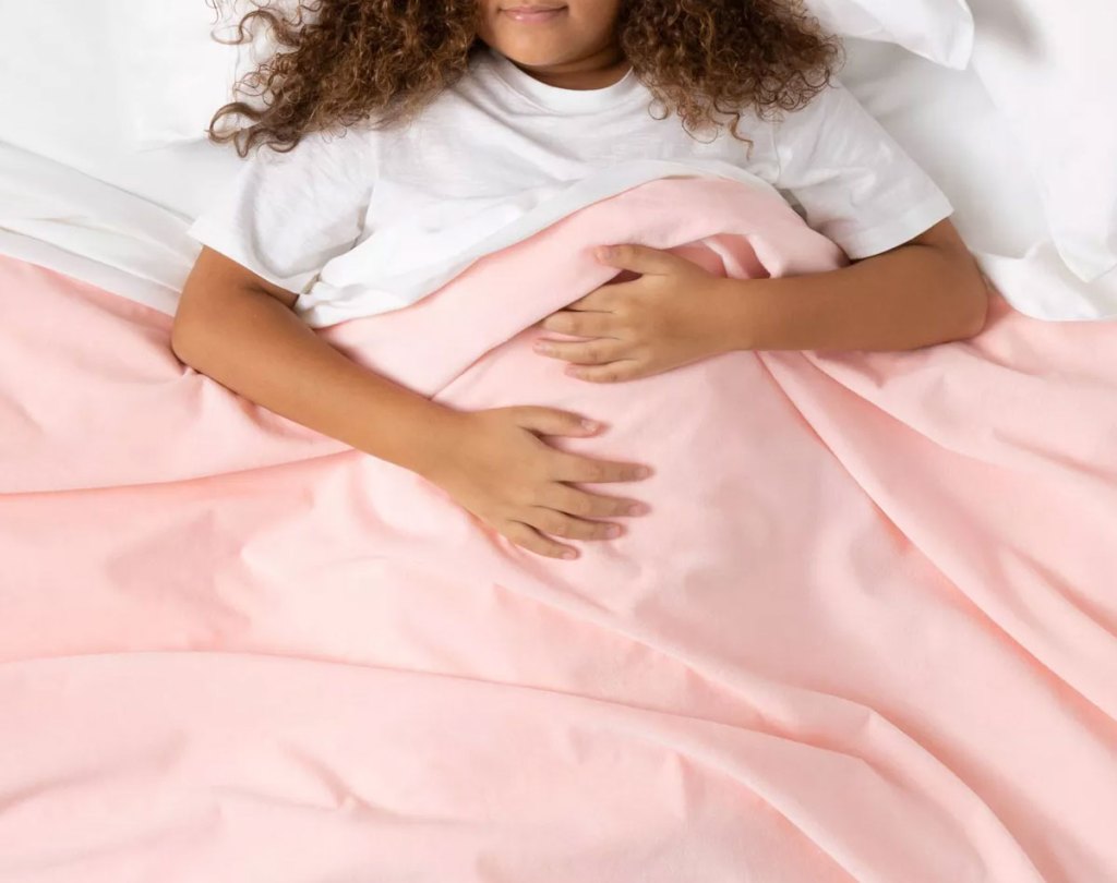 girl sleeping under a light pink weighted blanket