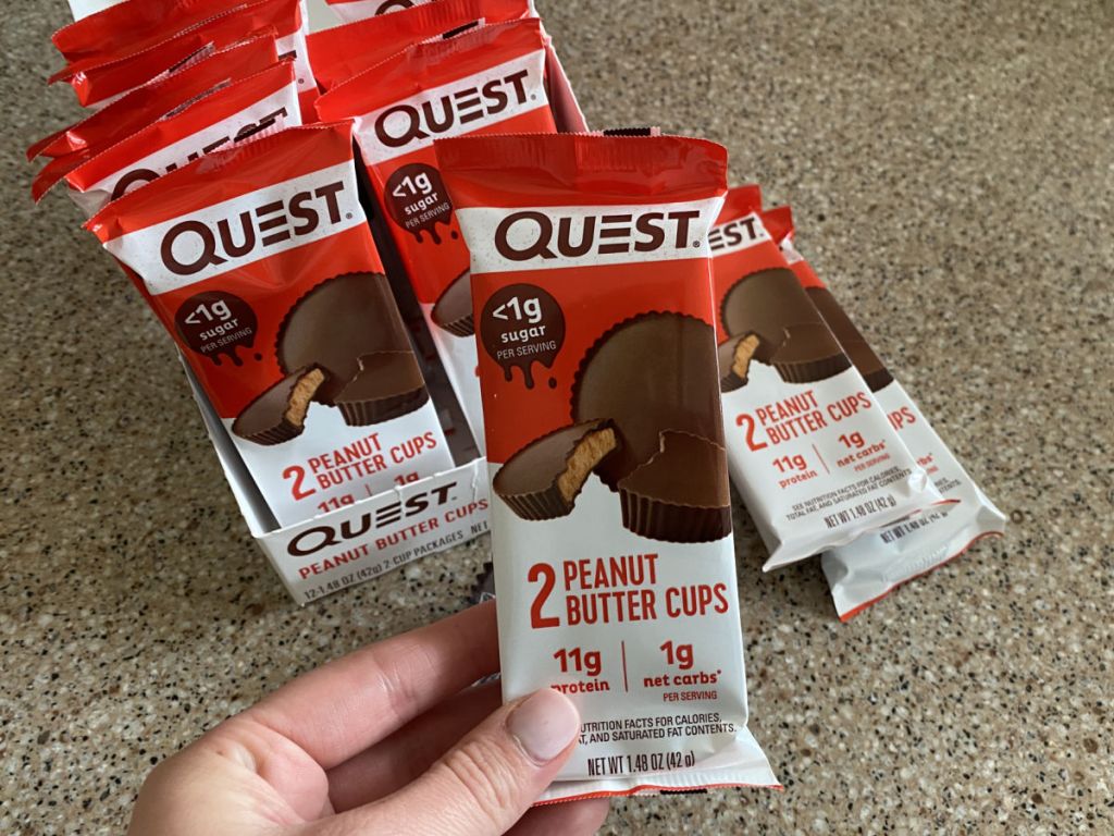 person holding up package of quest peanut butter cups