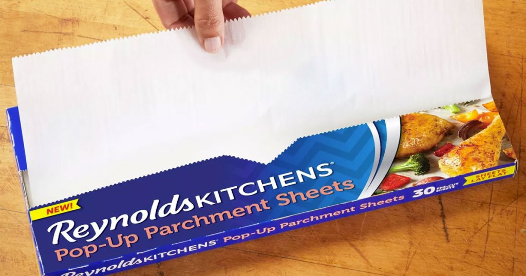 person pulling a parchment paper sheet from a blue reynold's box