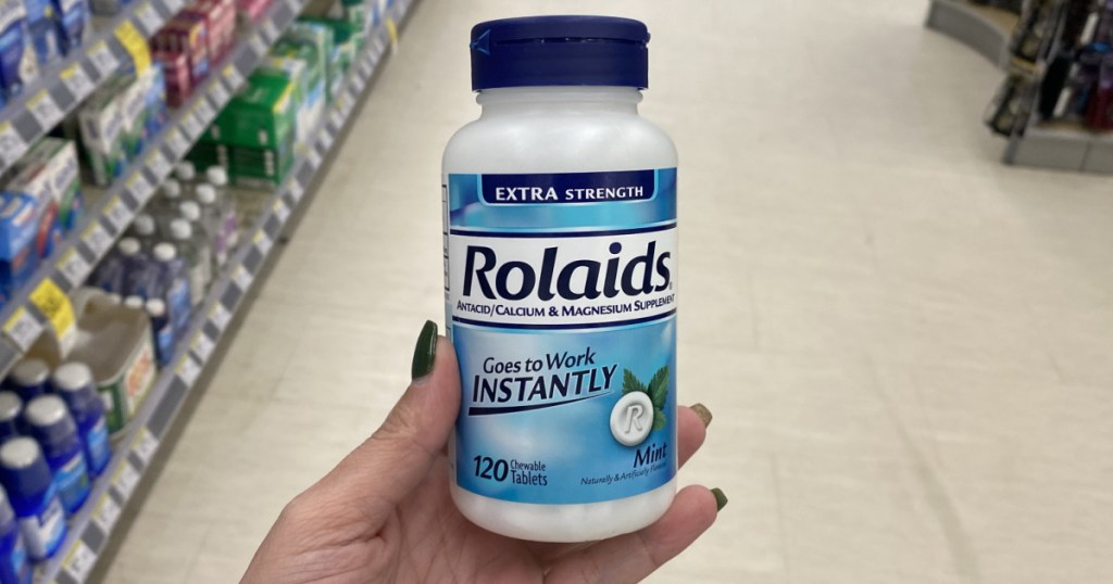 woman's hand holding bottle of antacids in store