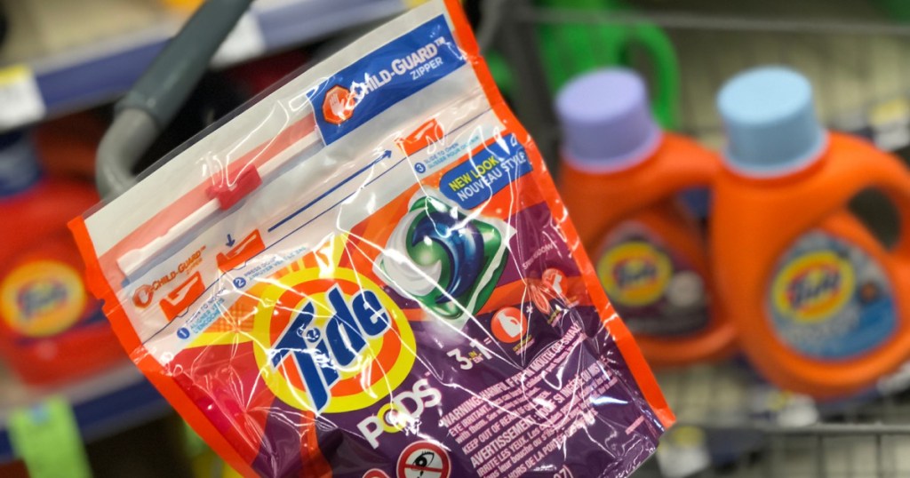 hand holding pack of tide pods with liquid in the background