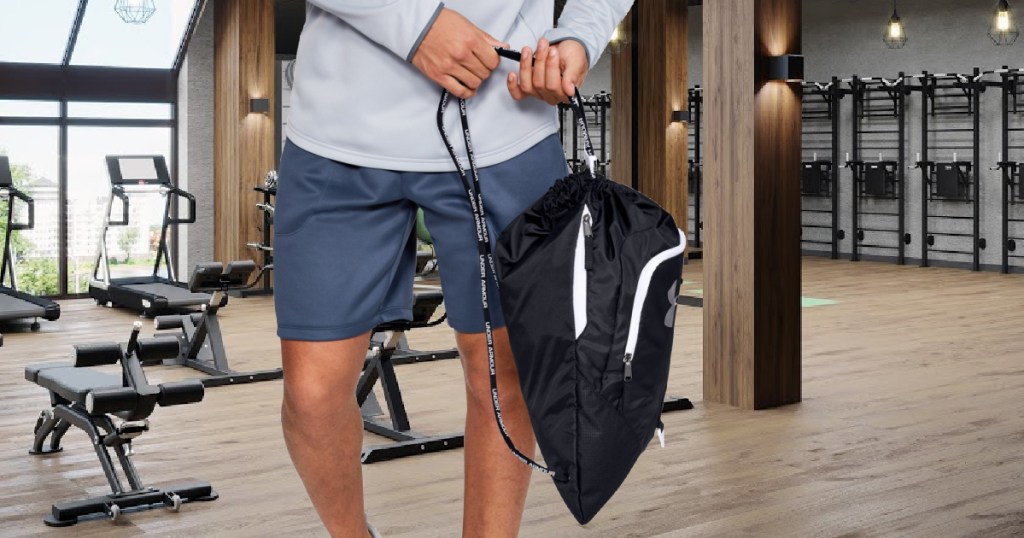 man holding black and white drawstring bag in gym