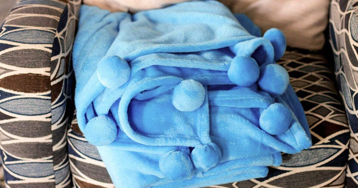 blue pom pom blanket folded up in a chair