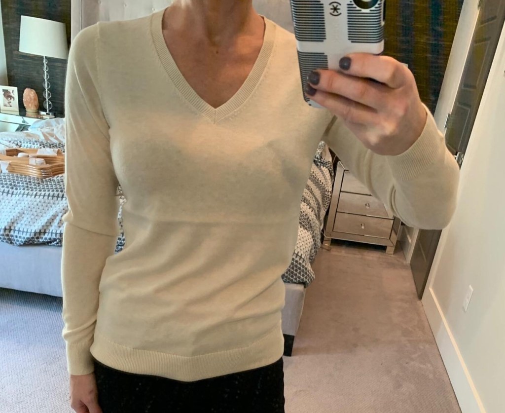 woman taking selfie in beige v-neck sweater