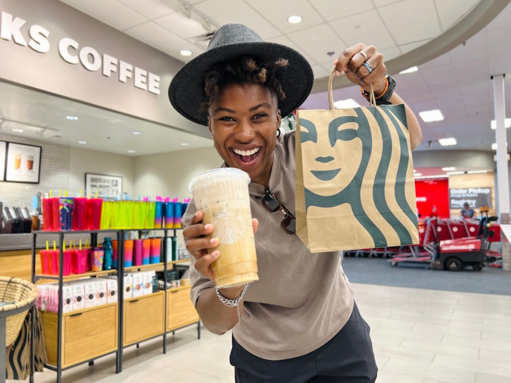 woman holding up starbucks drink and bag