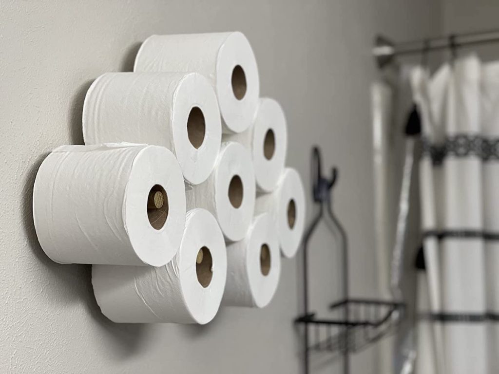 close up of toilet paper hanging on wall pegs in bathroom