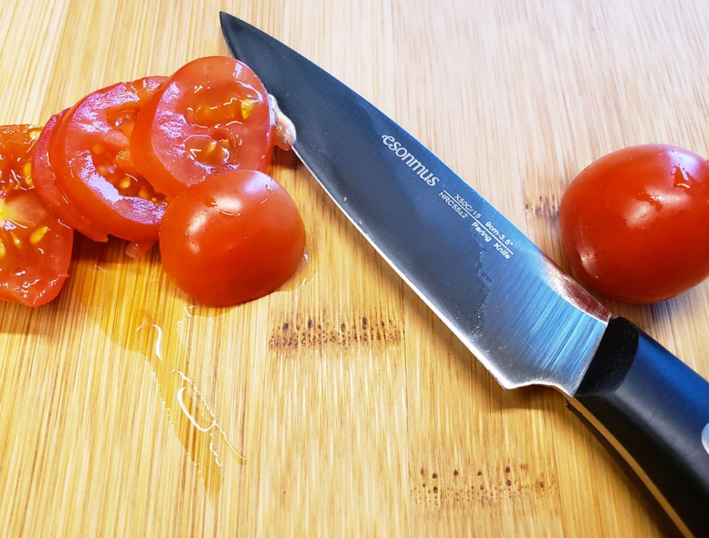 kitchen knife on cutting board with sliced tomatoes
