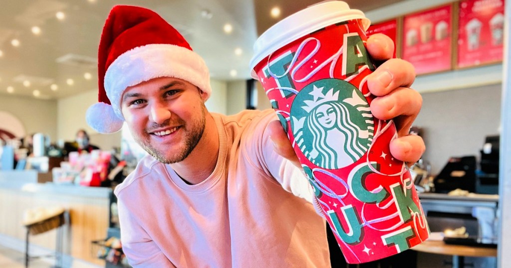 man holding a starbucks holiday cup
