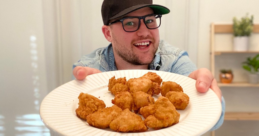 man holding plate of chicken nuggets