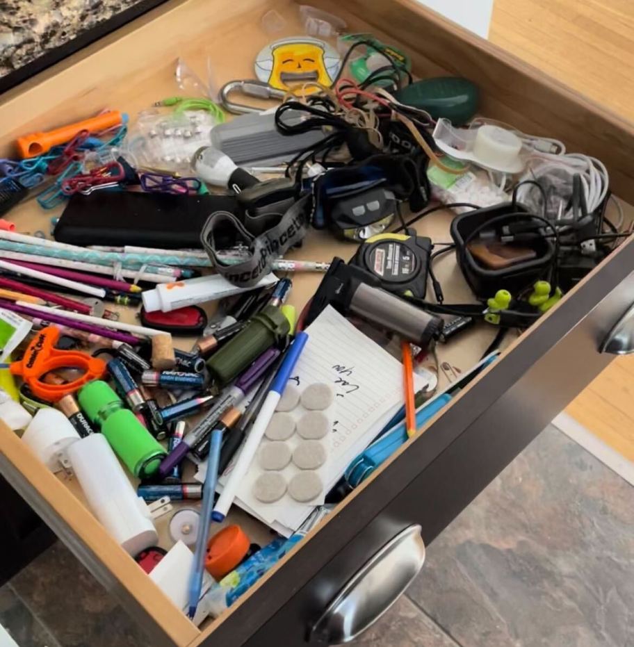 open kitchen junk drawer with various messy stuff inside
