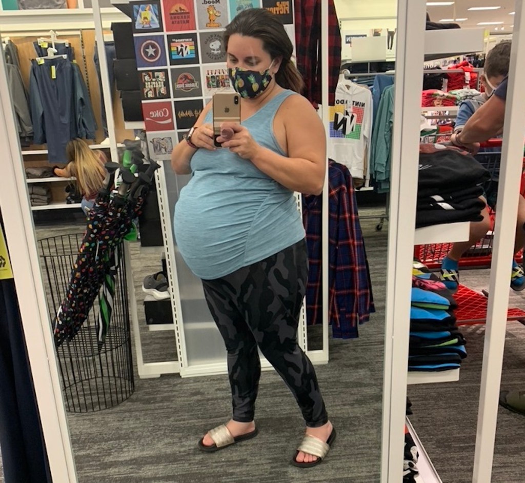 pregnant woman taking selfie in mirror wearing camo leggings and blue tank top
