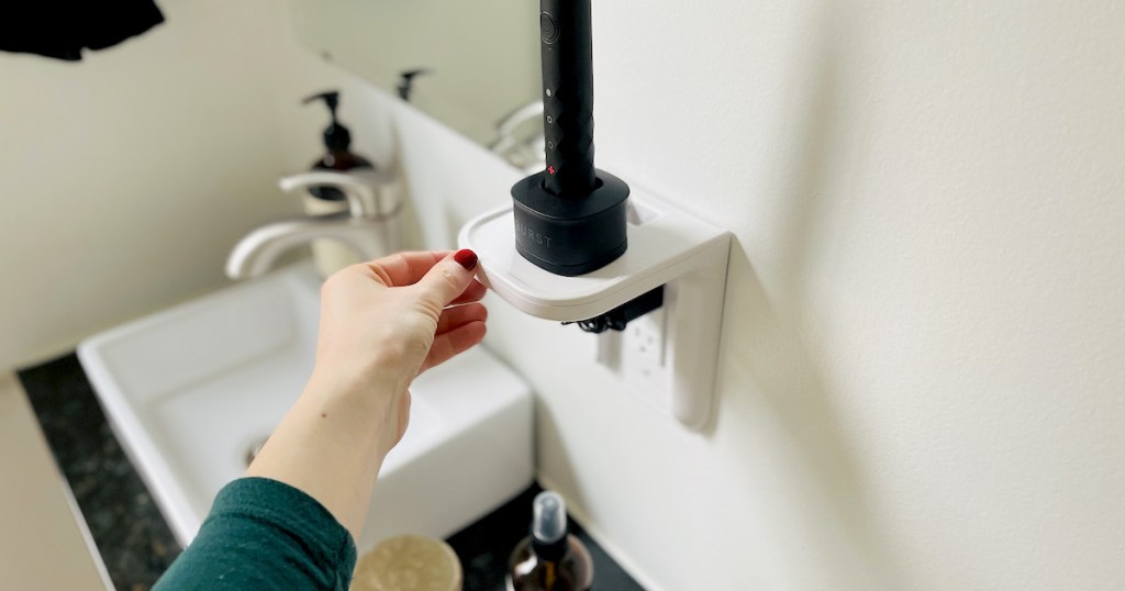 hand holding corner of a white outlet shelf for bathroom organization idea