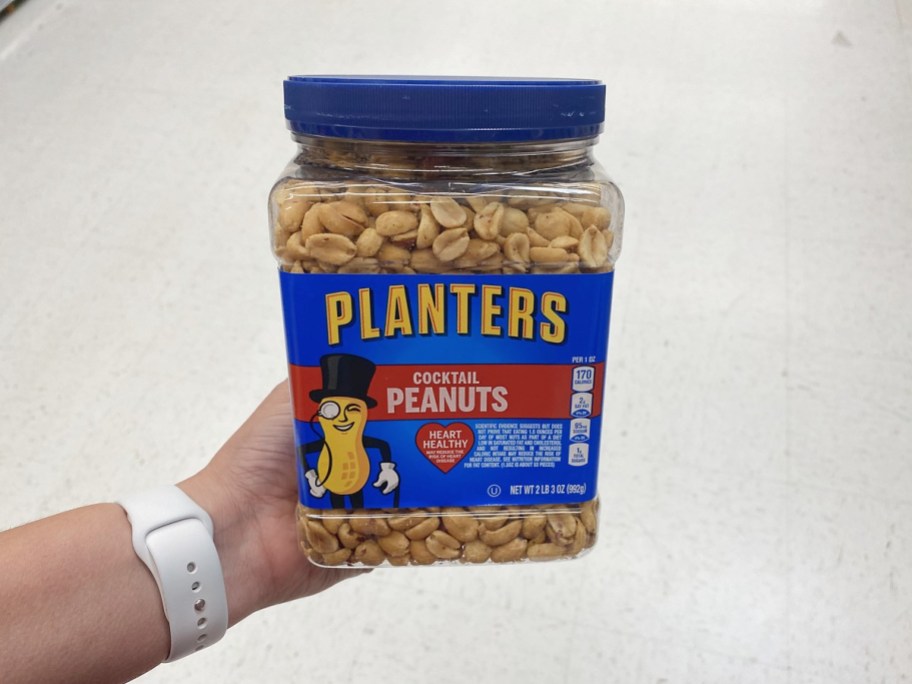 hand holding a large canister of planters cocktail peanuts