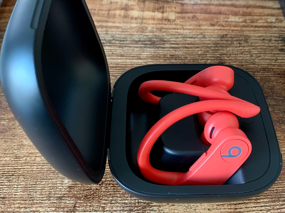 Pair of lava red wireless beats in black case on wooden table