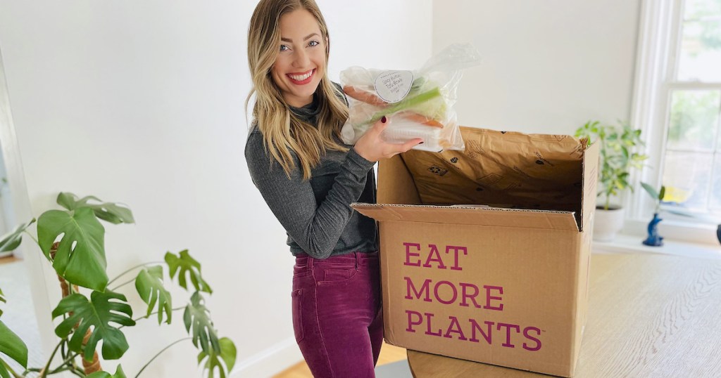 woman holding meal from eat more plants box on table