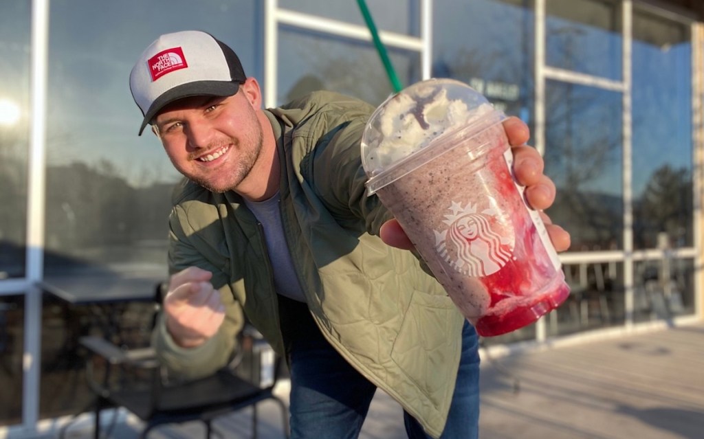 man holding starbucks frappuccino outside of store