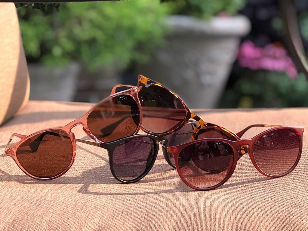 four pairs of sunglasses on patio furniture chair