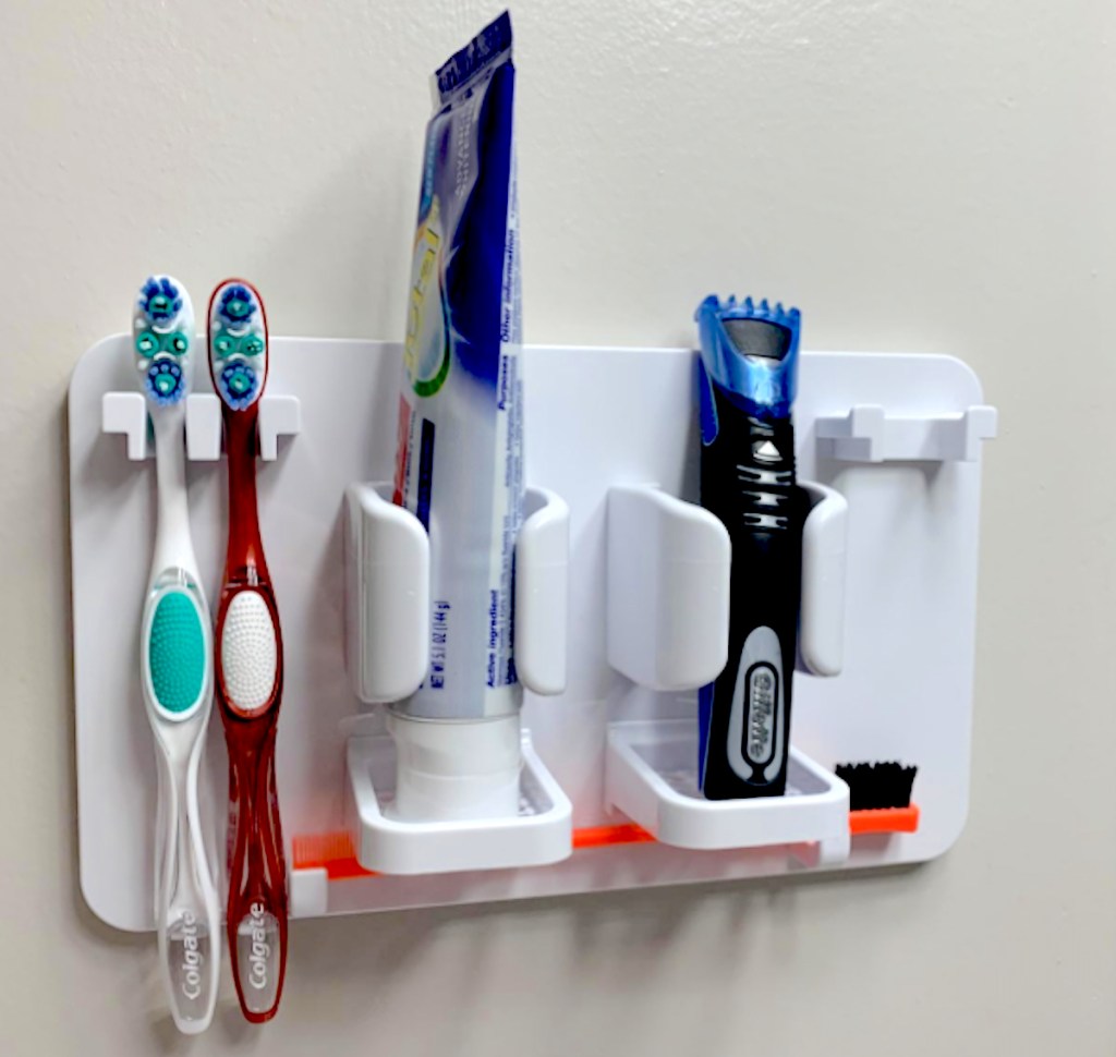 white toothbrush holder on wall with toothpaste and razor - bathroom storage ideas