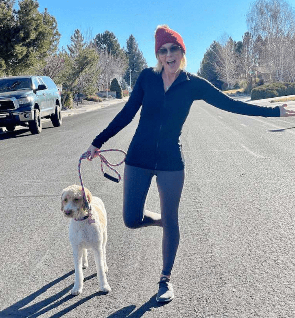 woman wearing leggings and jacket outside with dog 