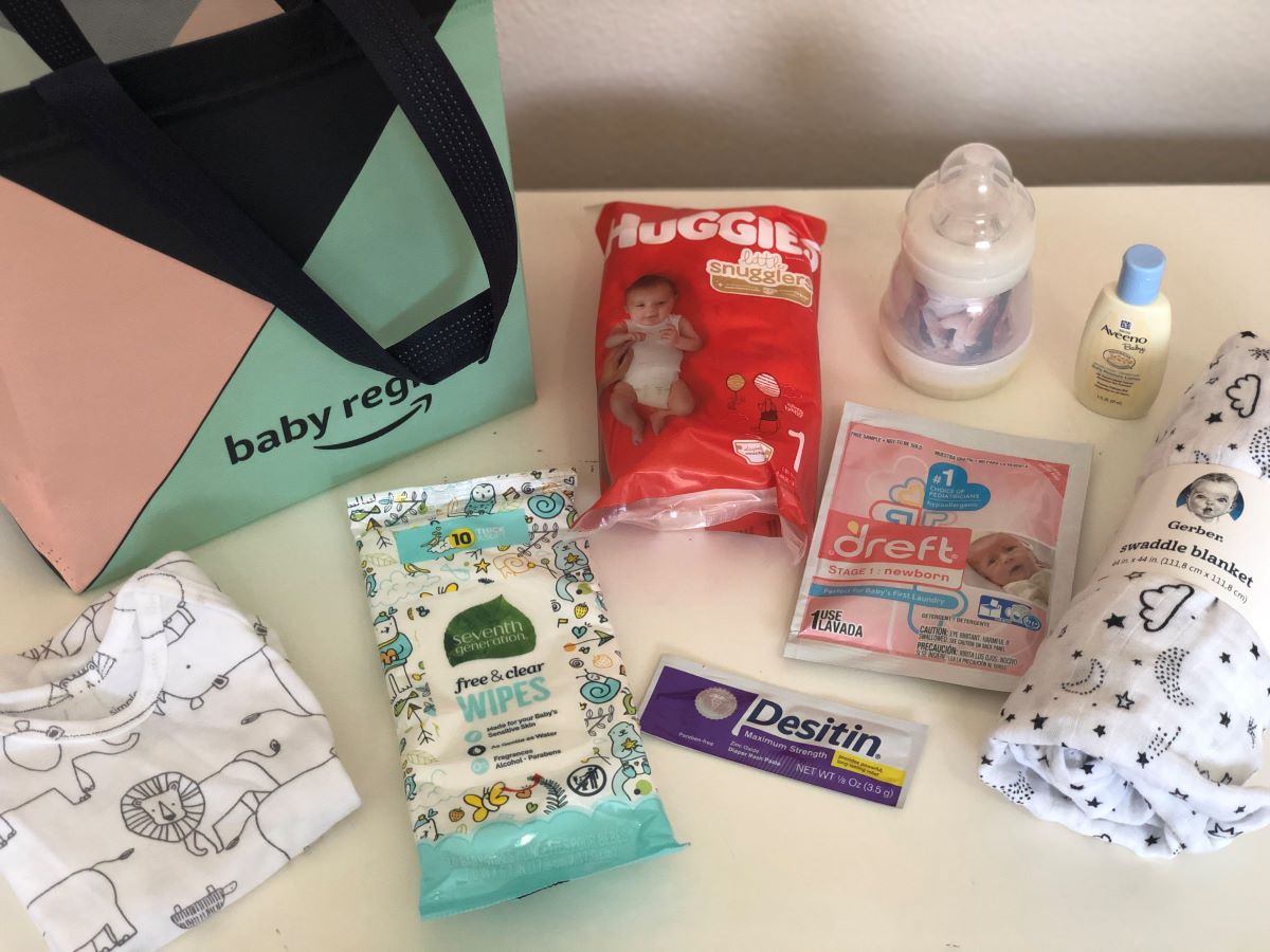 Amazon Baby Registry bag and samples on a table including Huggies diapers, a baby bottle, Seventh Generation wipes, Desitin, Dreft and a Gerber blanket.