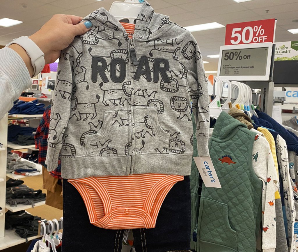 person holding up carter's outfit set with dinosaur hoodie that says roar