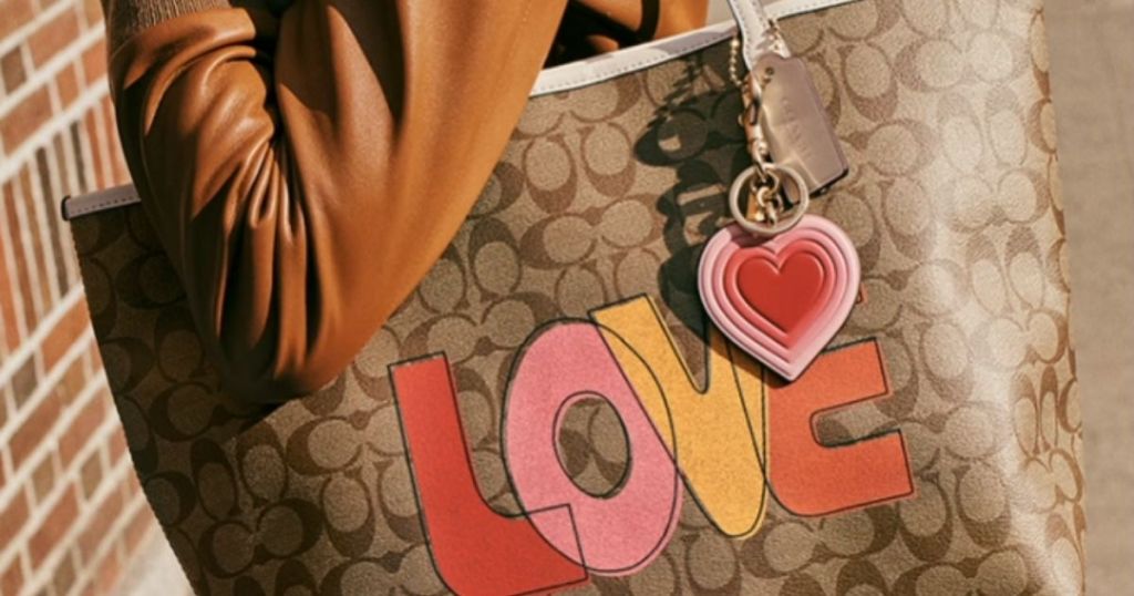 woman carrying a Coach bag that says love