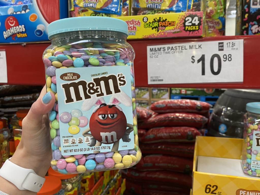handing holding a large jar of pastel m&m's at sam's club