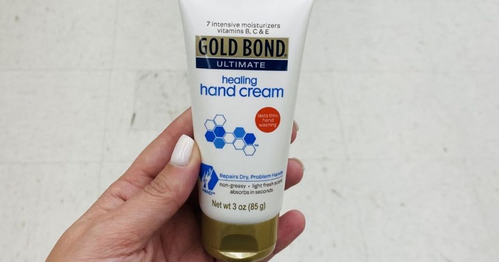 hand holding a bottle of Gold Bond Healing Hand Cream