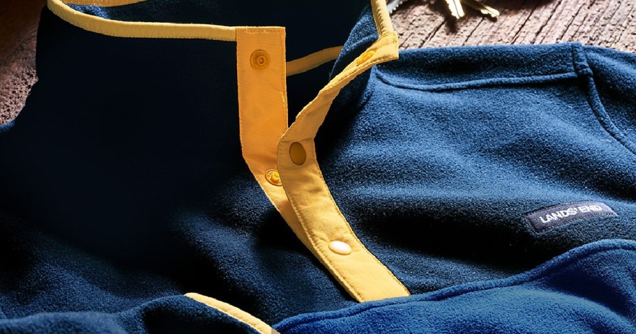 men's blue and yellow buttoned pullover on table next to keys