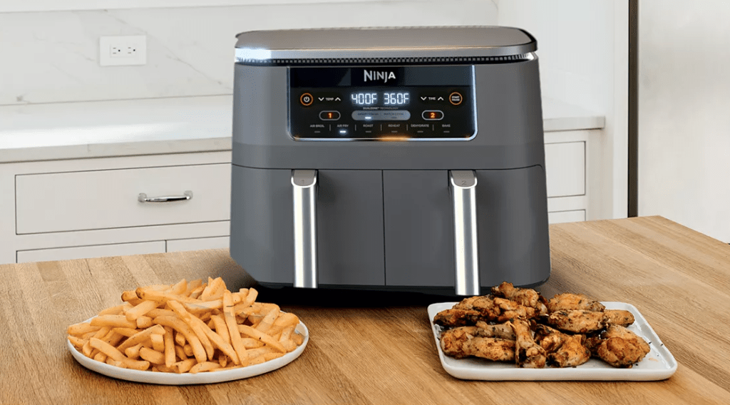 dual air fryer with plates of food in front of it
